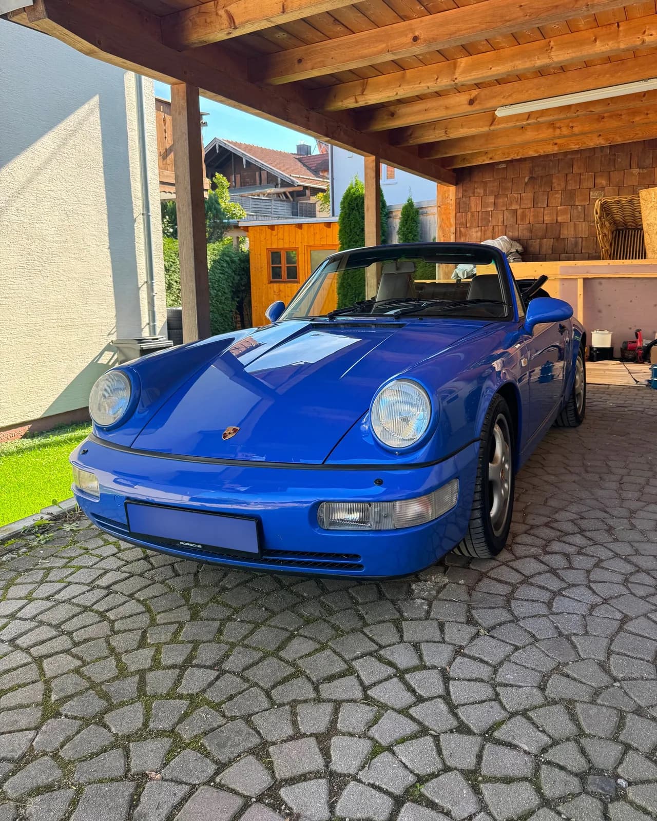 Porsche 964 Carrera 2 Cabriolet in Maritime Blue under a wooden carport